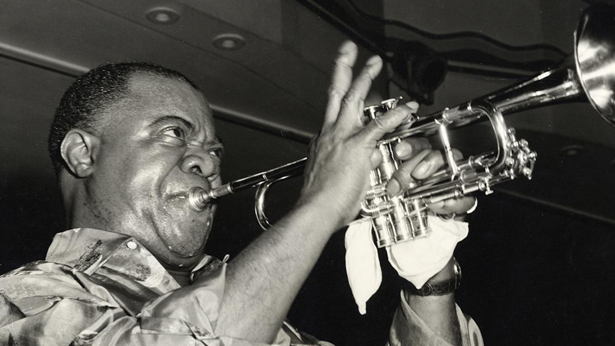 black and white photo of Louis Armstrong playing the trumpet