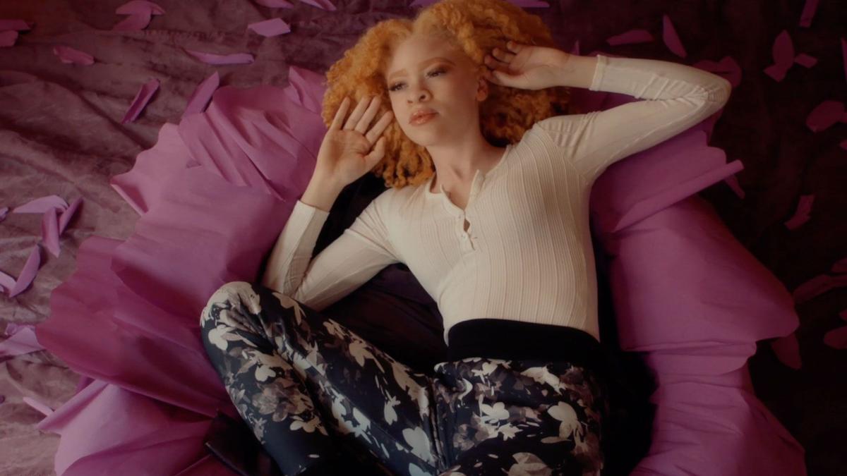 girl laying on pink bed with hands on head