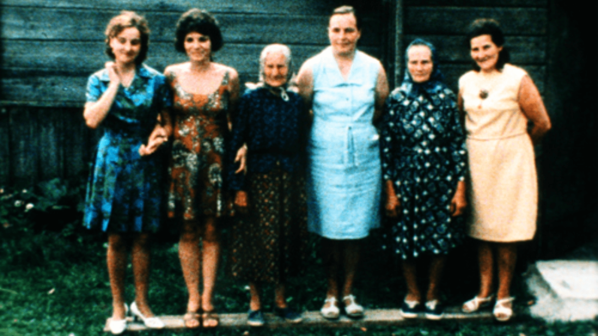 group of 6 woman standing against wall next to each other with dresses on