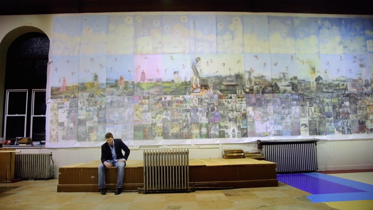 man sitting on bench in front of large mural
