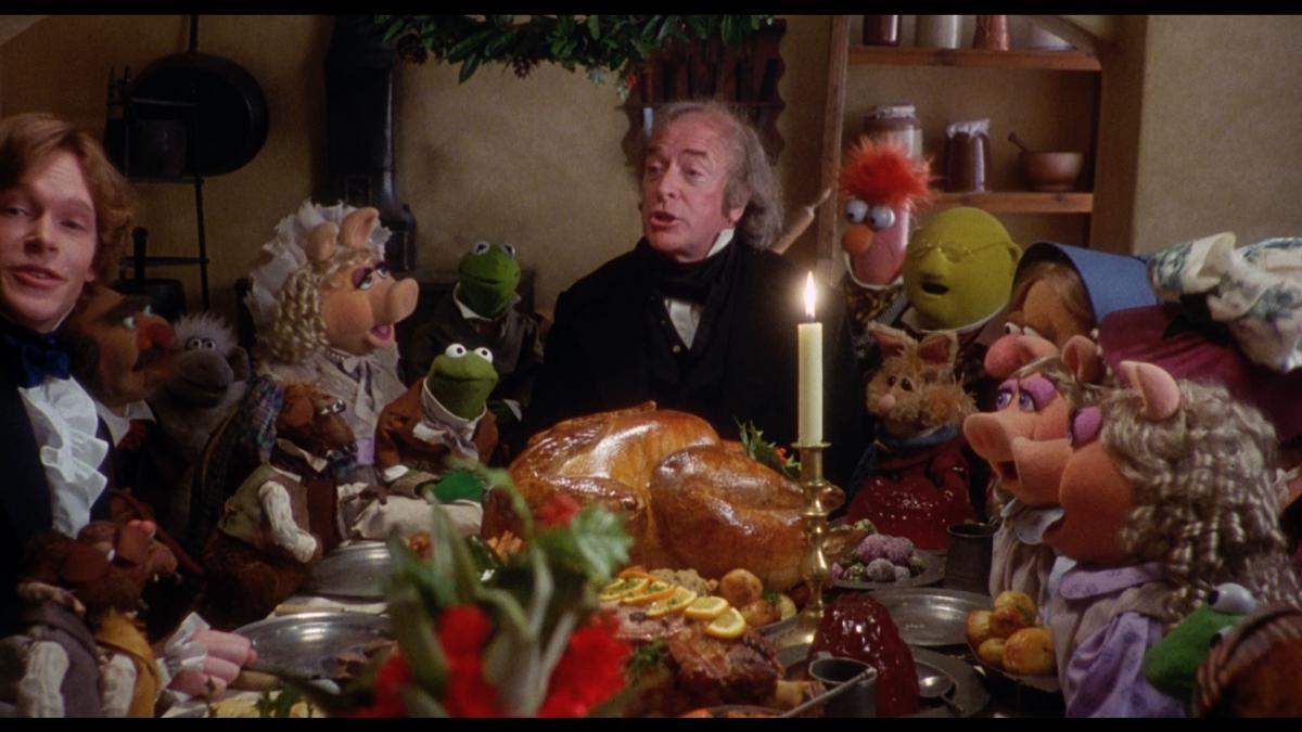 man sitting around table with food and the muppets