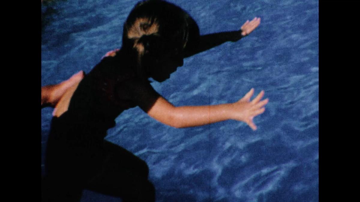 young girl jumping into pool with hands outstretched