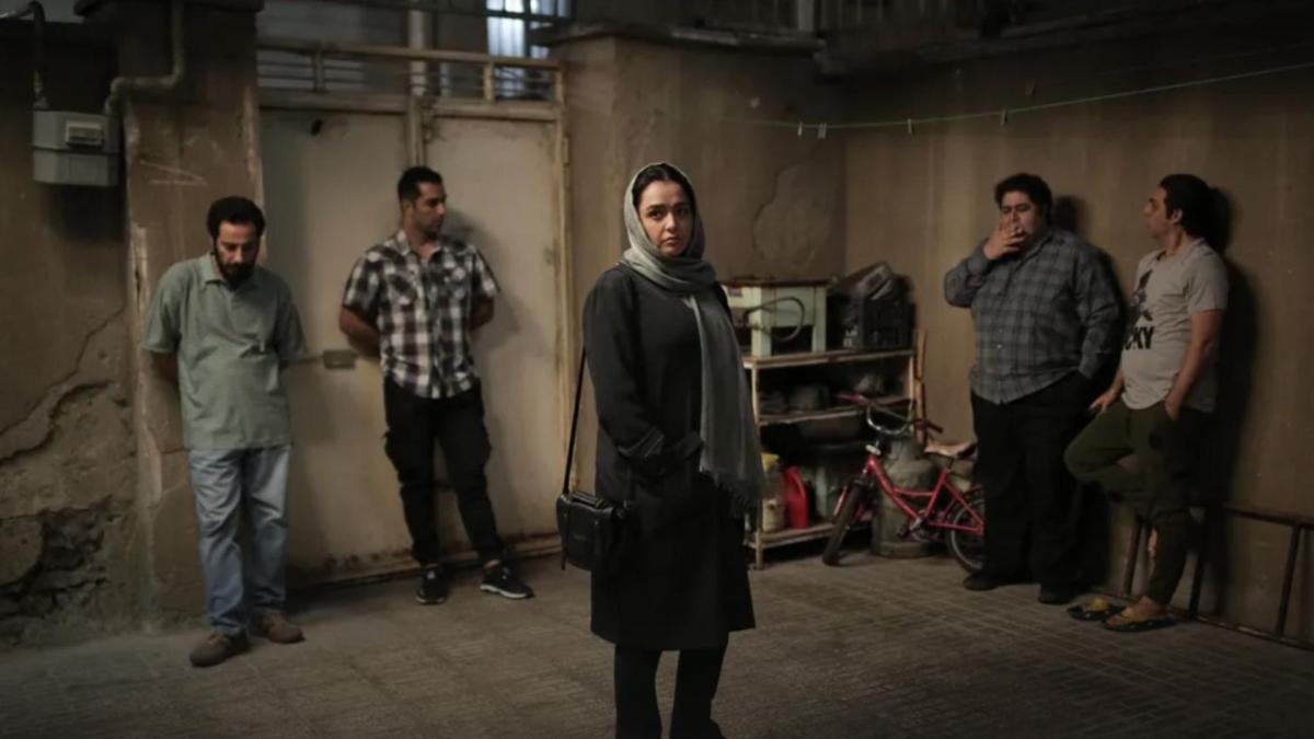 woman standing in middle of basement with four men leaning against walls in background