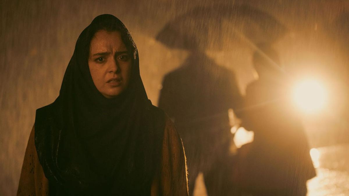 woman wearing hijab in the rainy street with couple holding umbrella in background