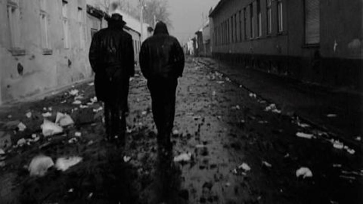 backs of two men walking away on dark, wet street