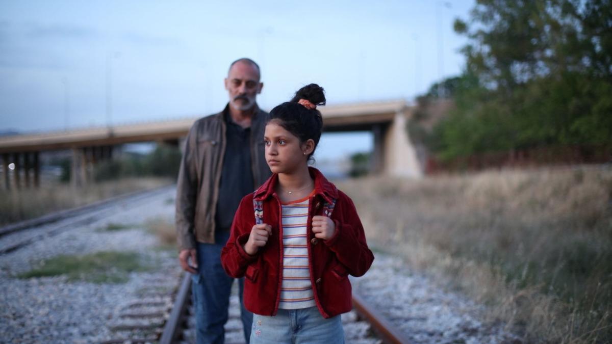 man and young girl walking along railroad tracks