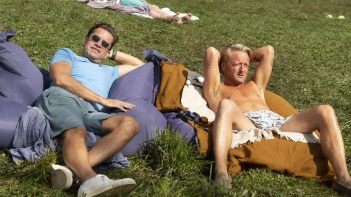 two men lounging in the grass on blankets