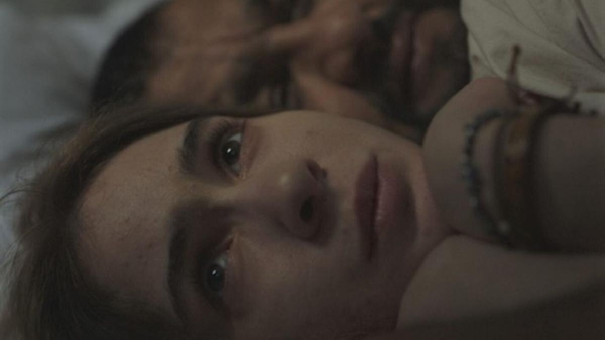 close up of woman with eyes open in bed sleeping next to man