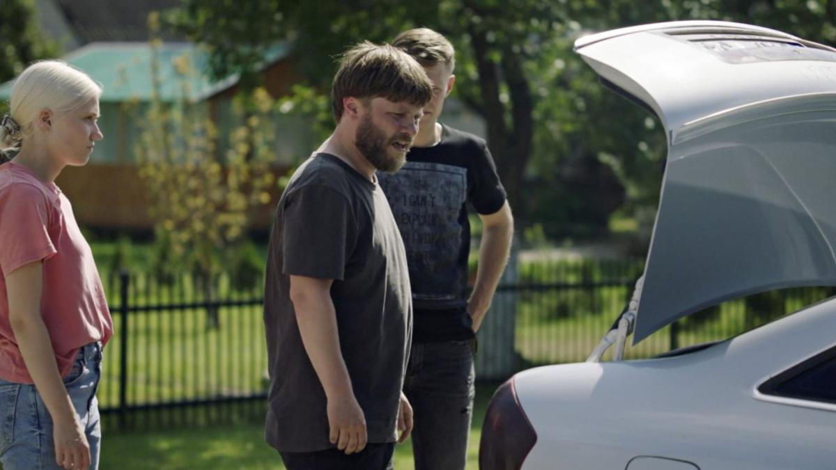three young people standing outside by car with trunk door open