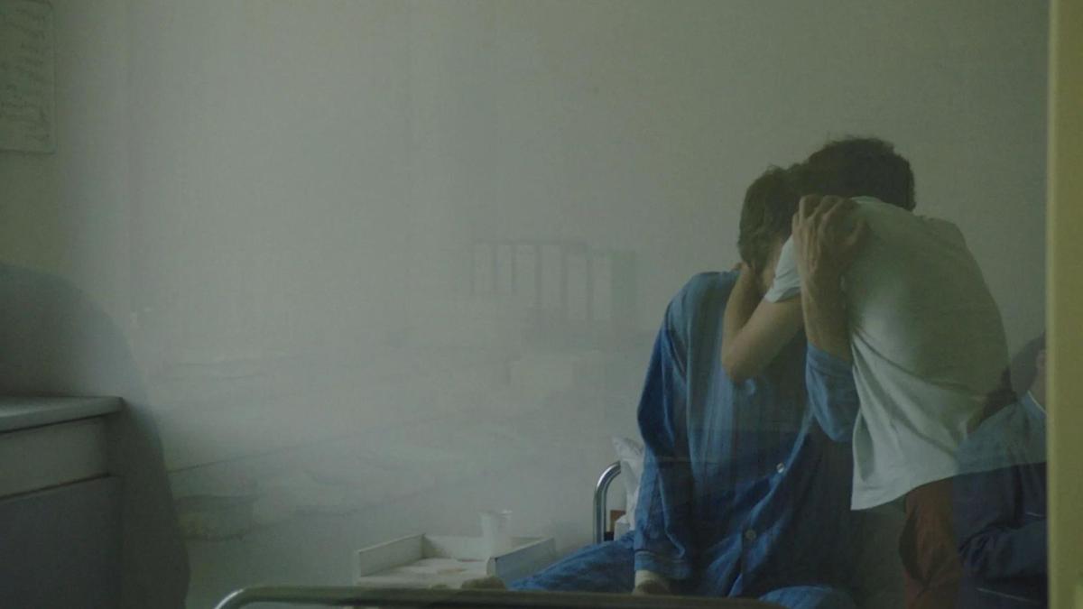 couple sitting on bed hugging