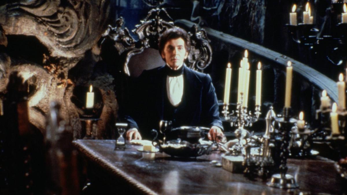 Dracula sitting at end of long dining table with candles