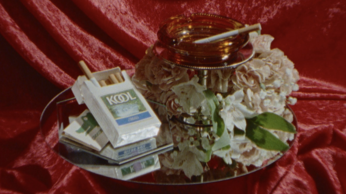 pack of cigarettes, ash tray, and flowers on silver tray on red vlevet fabric