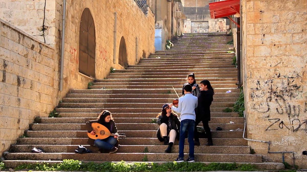 people sitting on steps and someone playing guitar
