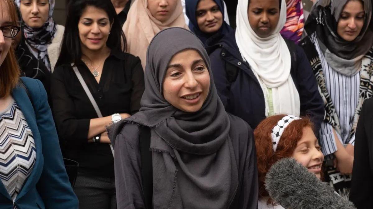 crowd of people with woman wearing hijab in center