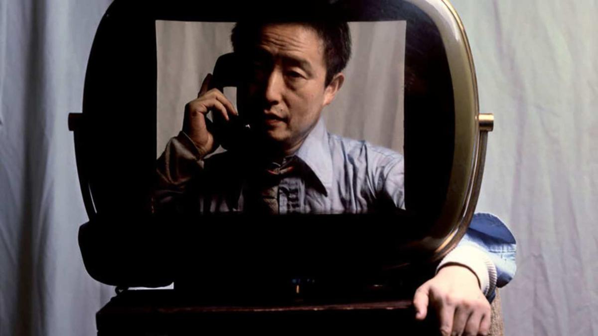 man wearing dress shirt on phone staring through monitor