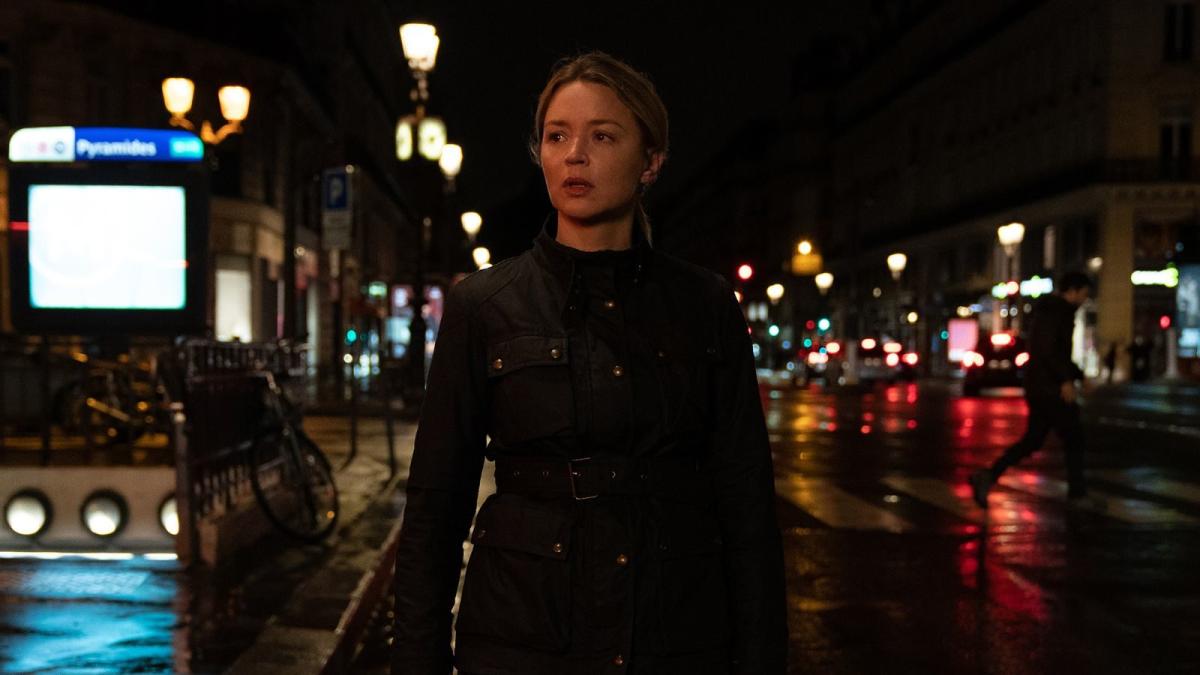 woman wearing black jacket walking through street at night