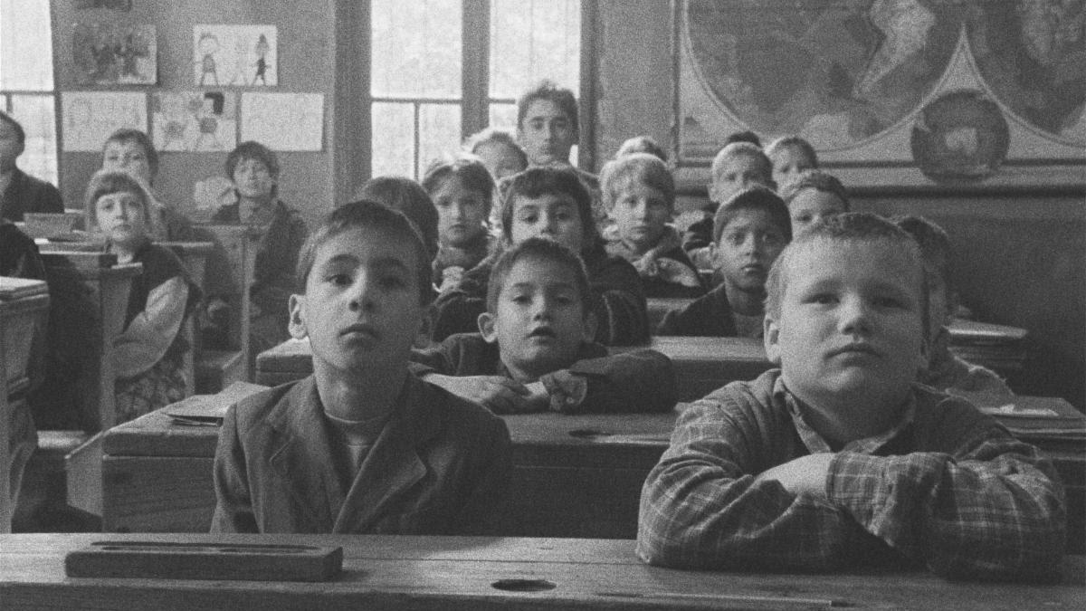black and white image of young children sitting at school desks looking forward