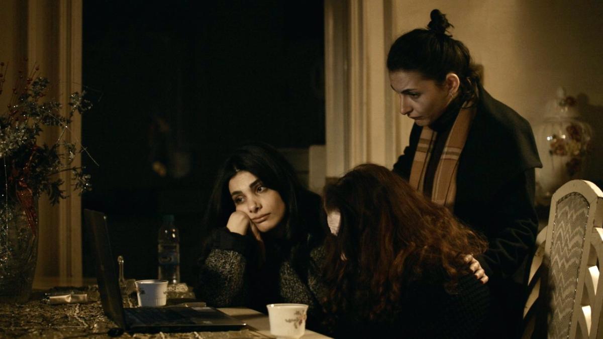 three women sitting at dining table looking at laptop