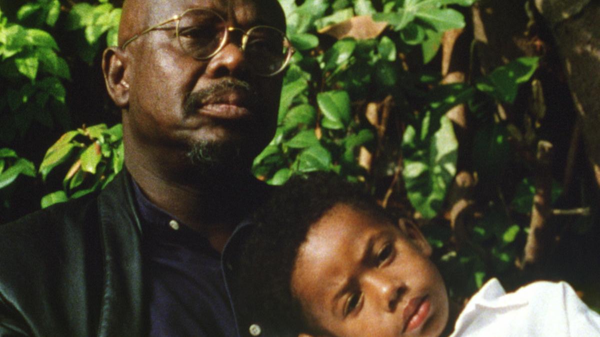 man and young girl sitting outside with girl sleeping on his shoulder