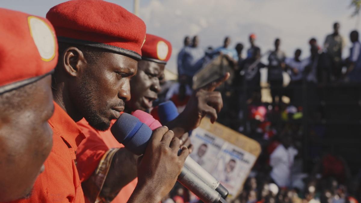 man in cap speaking to audience with microphone
