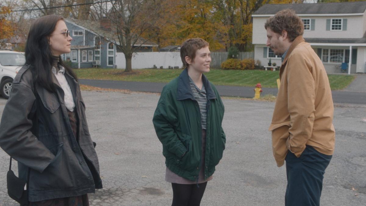 three people standing in street talking wearing coats