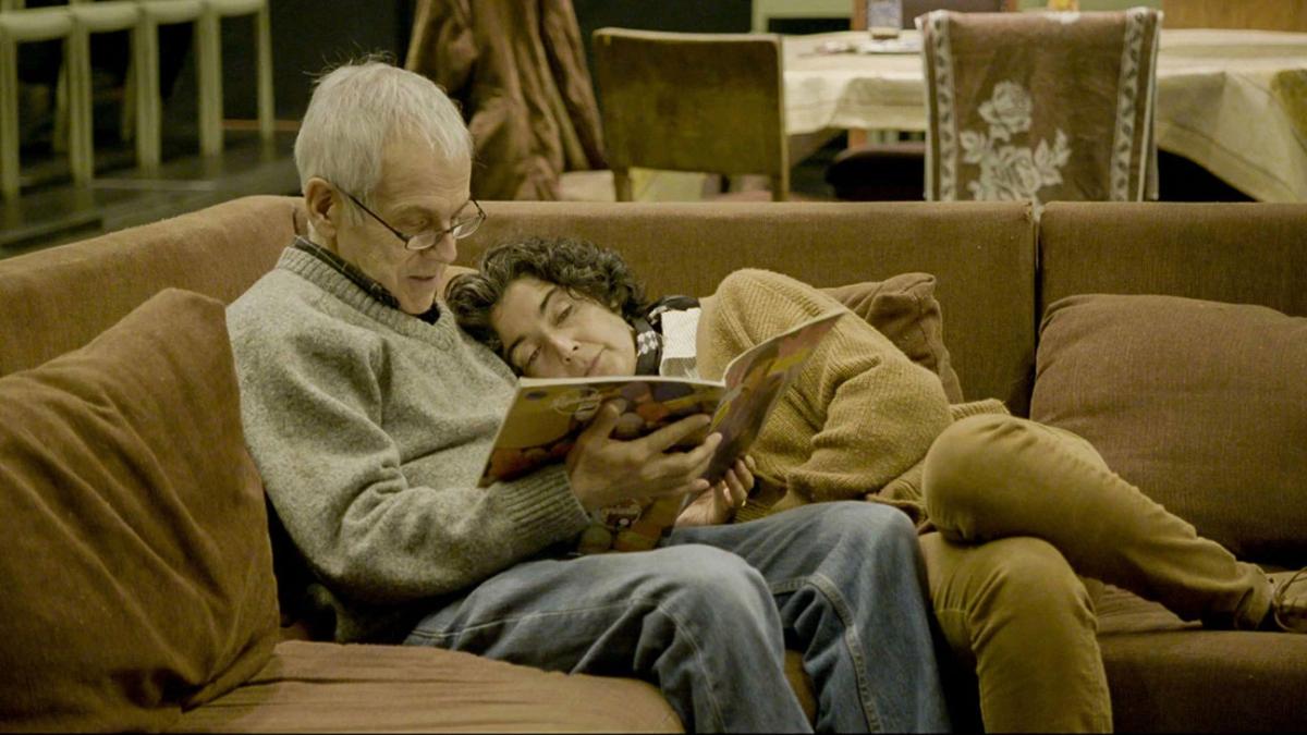 couple laying on couch reading book together
