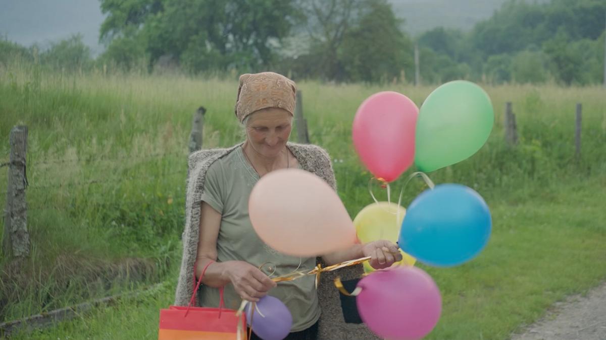 woman standing outside holding colorful ballooons