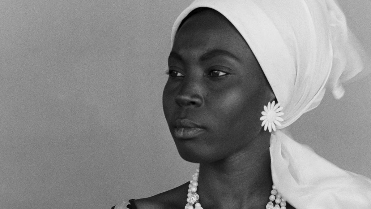 Black woman in white head scarf and earrings looking into distance