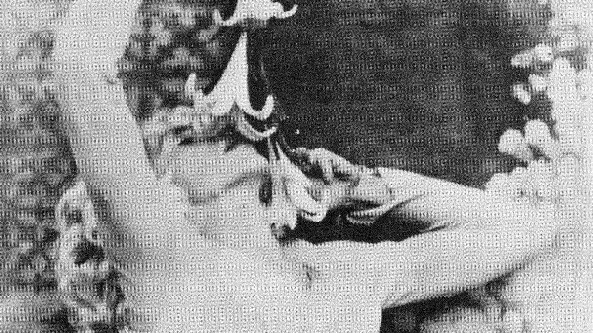 woman leaning back holding flowers above face