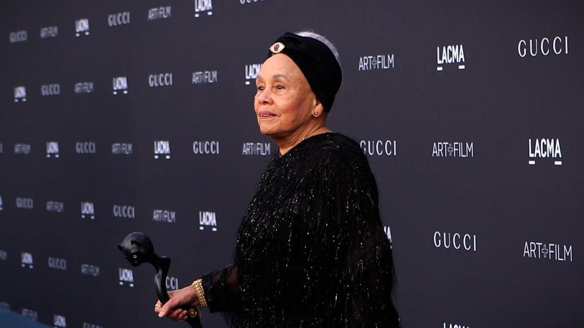 woman wearing black velvet gown on red carpet step and repeat