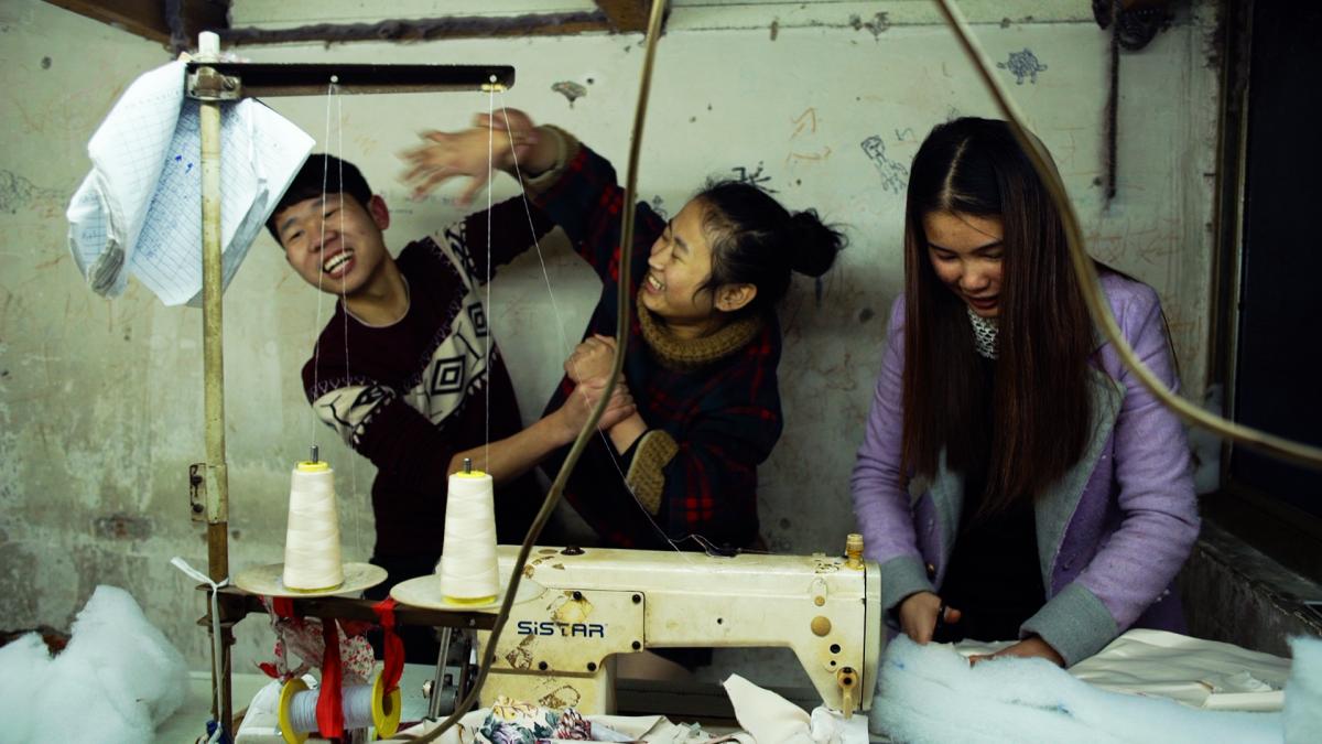 young people laughing and playing in front of sewing machine