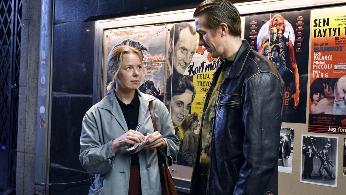 man and woman looking at each other on street in front of theatre