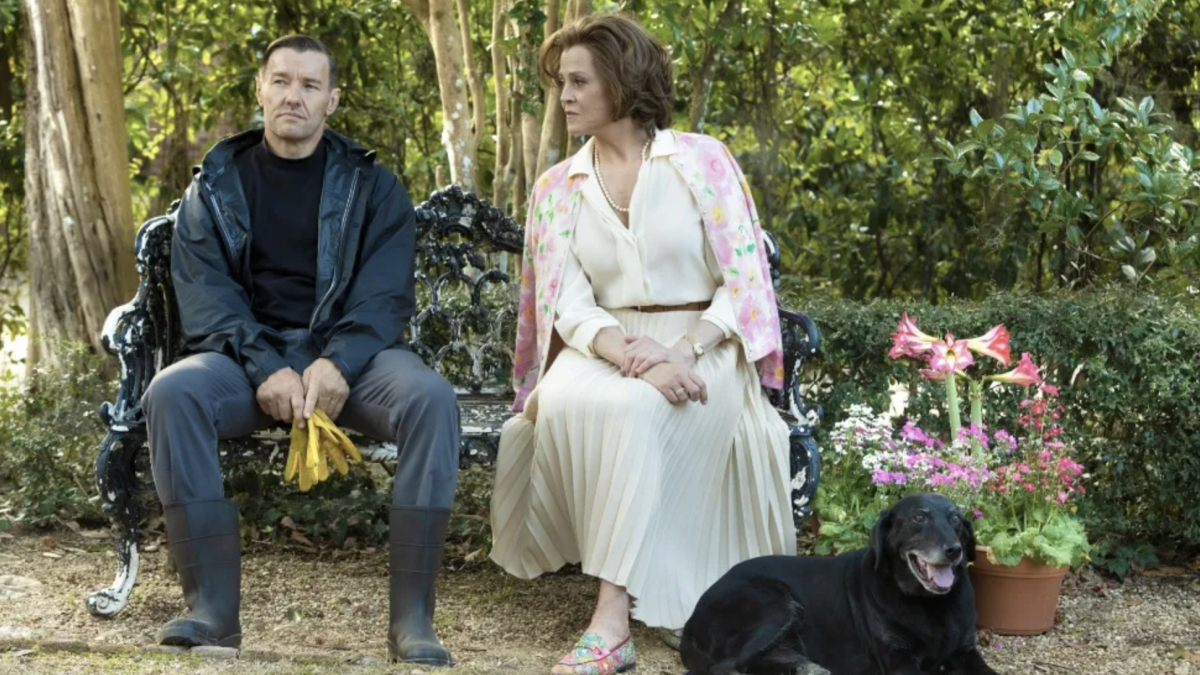 man, woman, and dog sitting on a bench in garden