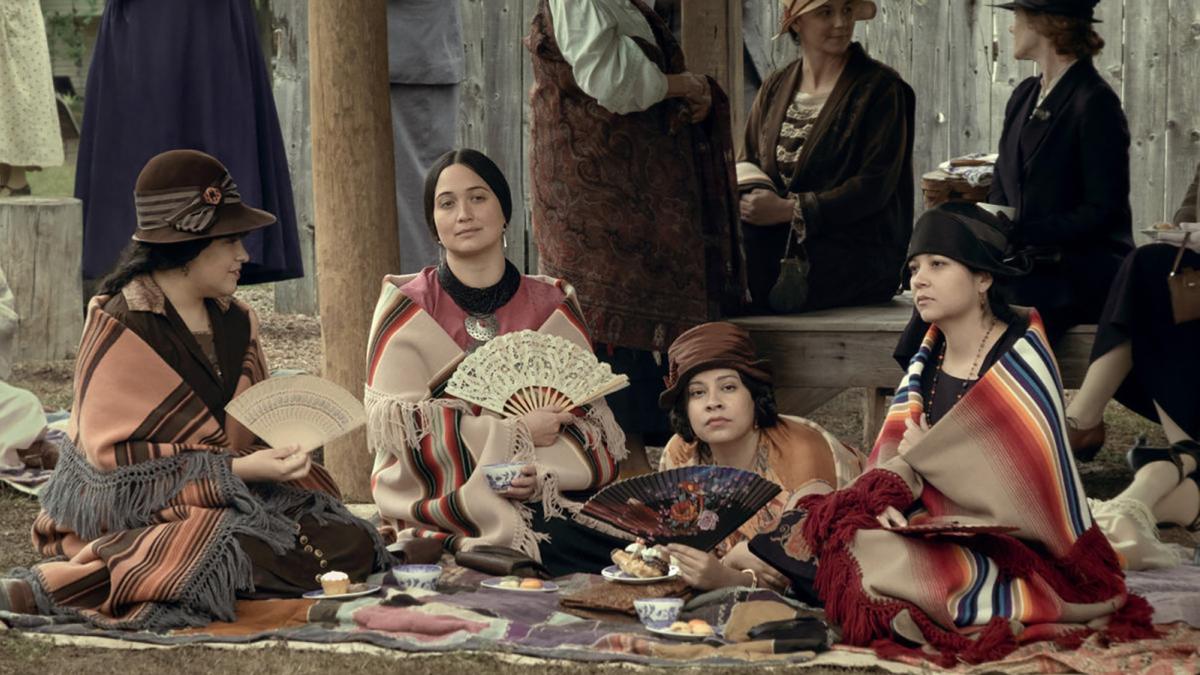 native american women in tribal blankets sitting down and fanning themselves