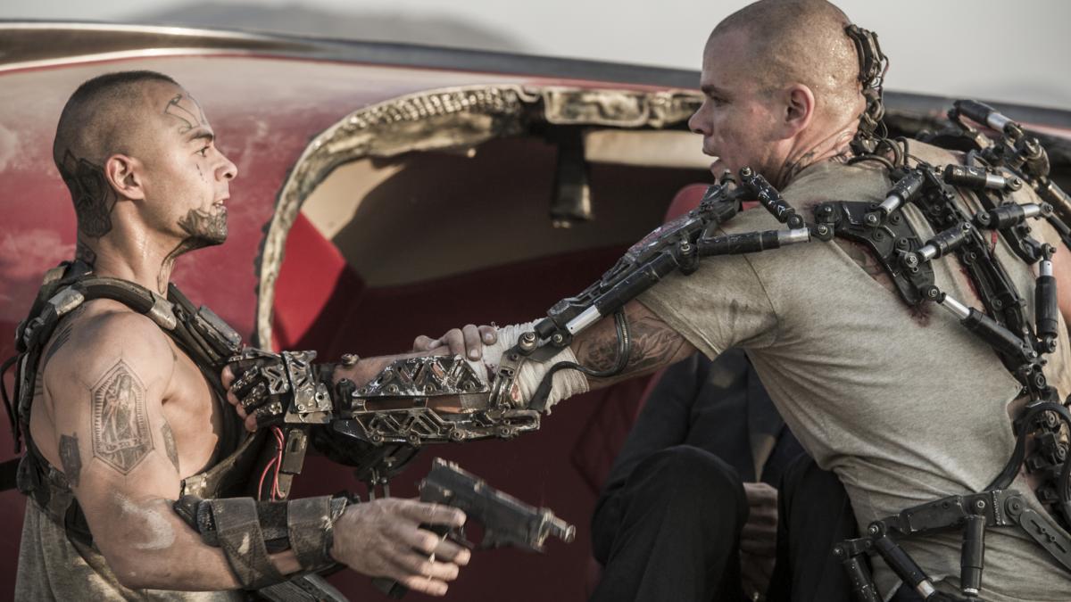 two men with weapons in front of burnt up car