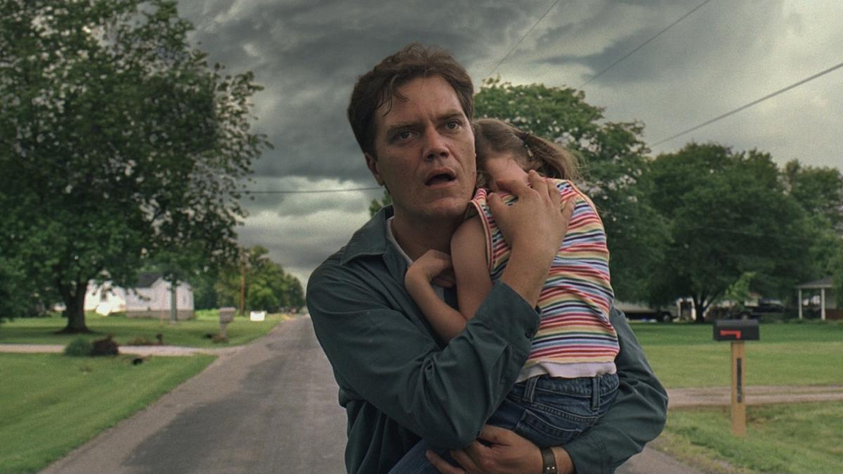 man holding young daughter in street with dark storm clouds behind