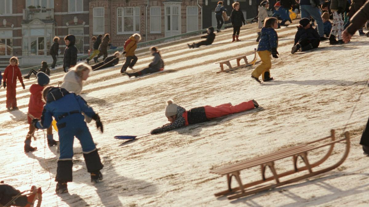 children playing in snow with sleds