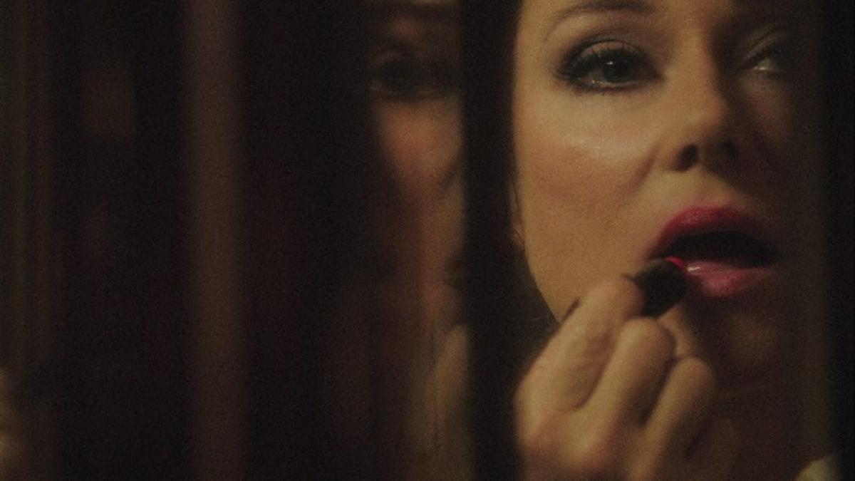 woman applying lipstick in mirror