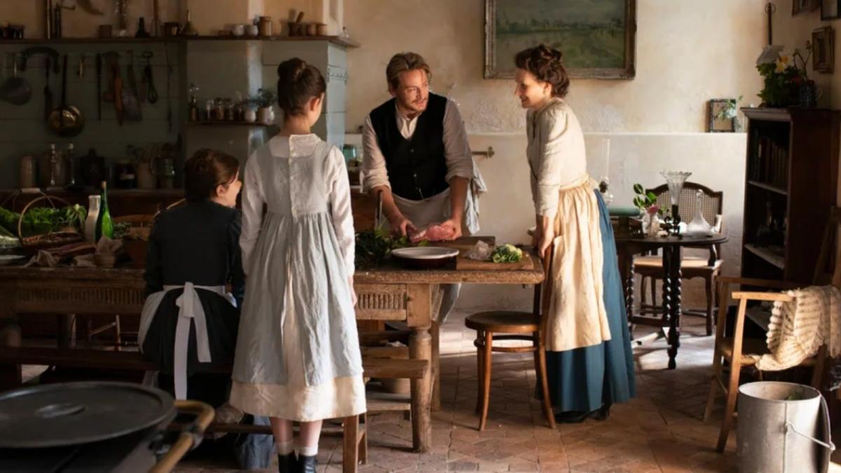 man and two women standing in rustic kitchen