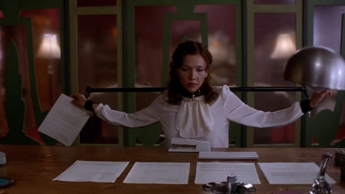 woman sitting at desk with collar around neck and arms outstretched