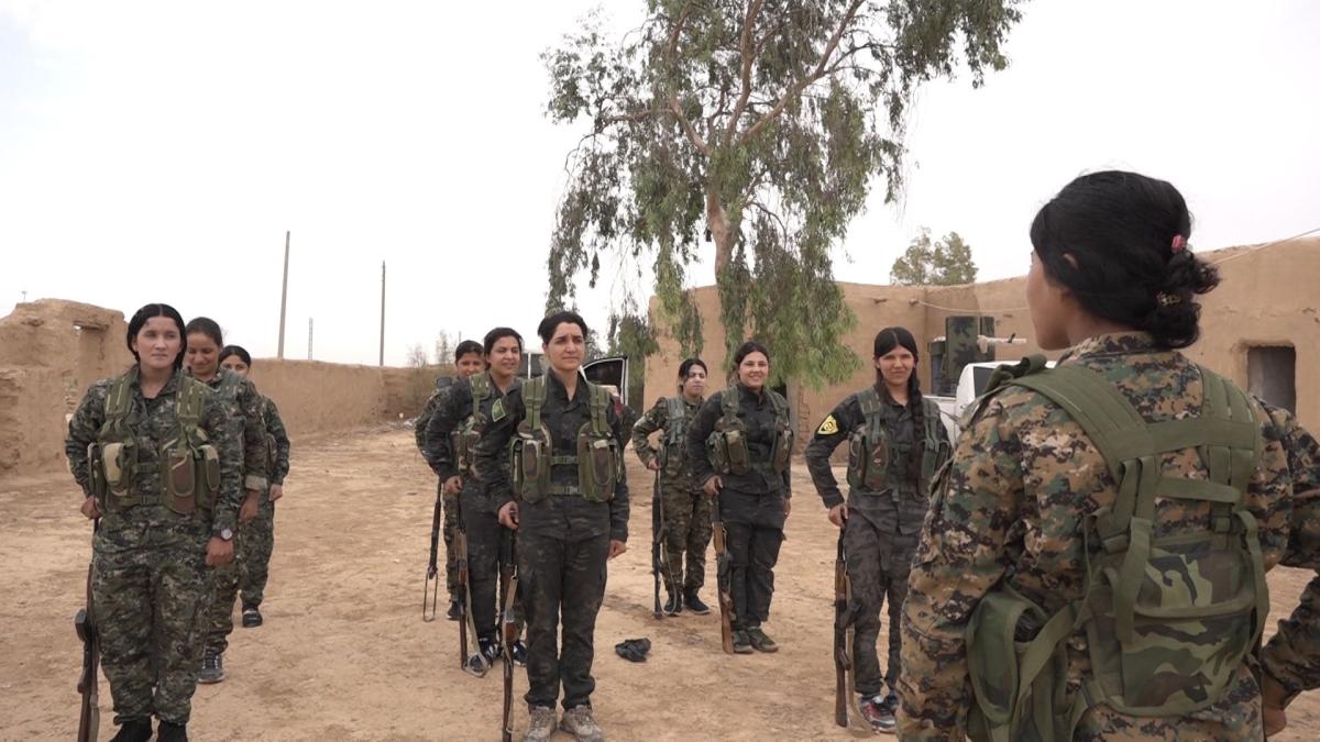 group of female soldiers standing in rows in desert landscape