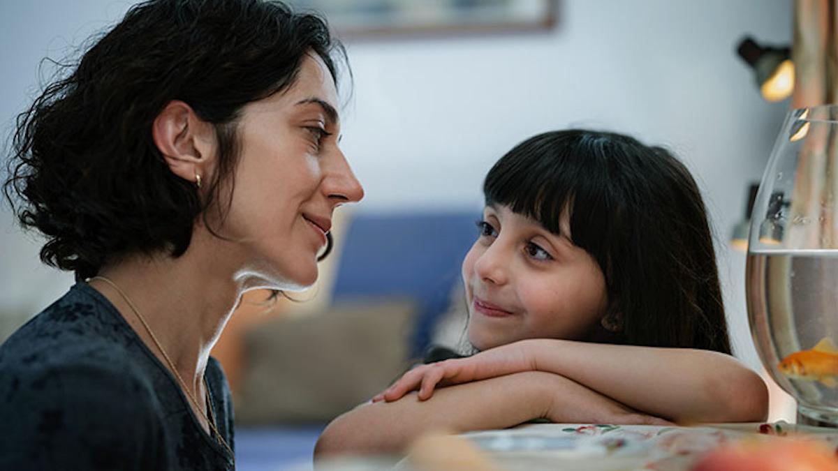 mother and daughter looking at each other in kitchen near fish bowl