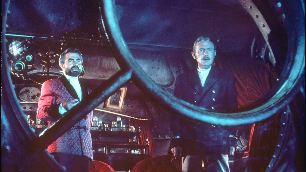 two men in submarine looking out glass window