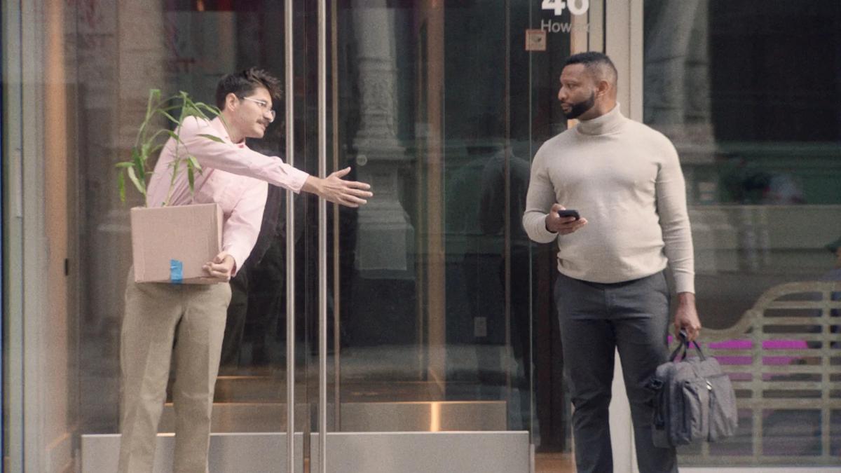 man holding box with plan outstretching hand to other man with briefcase and turtleneck