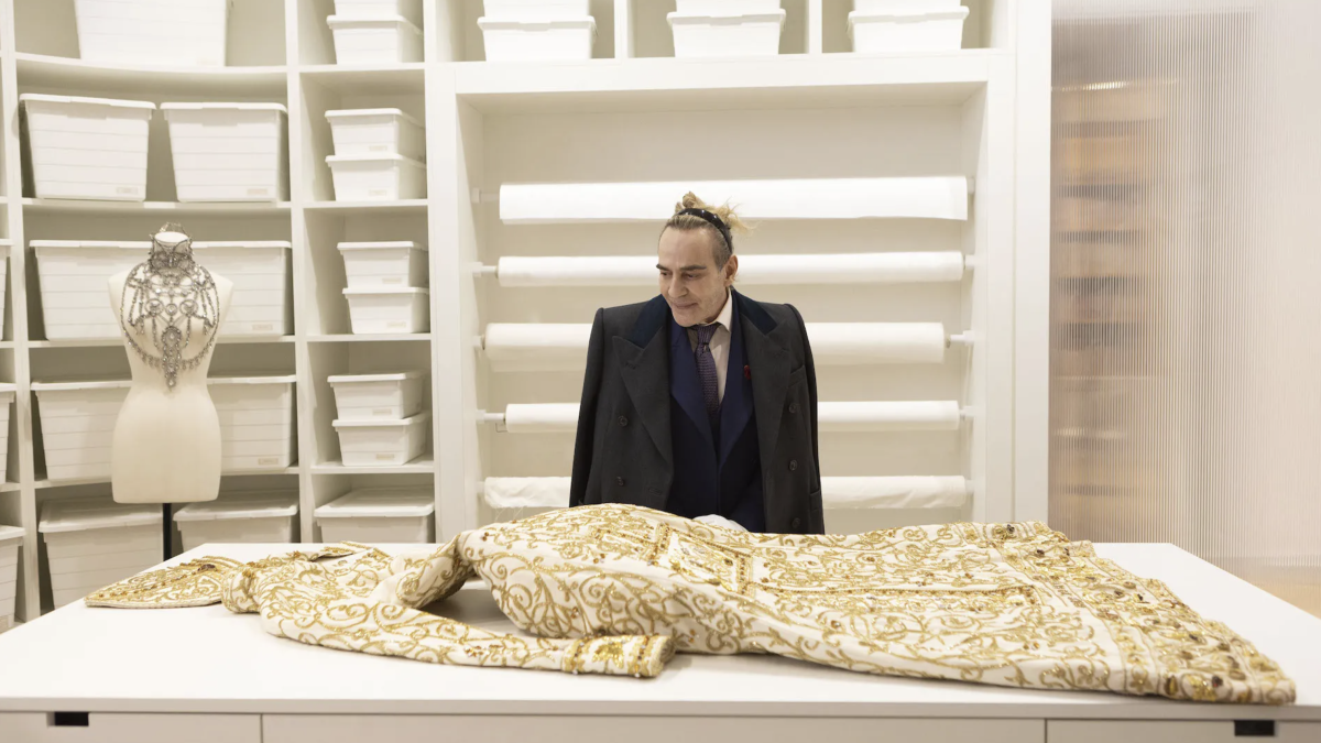 man in studio looking at extravagant dress on table