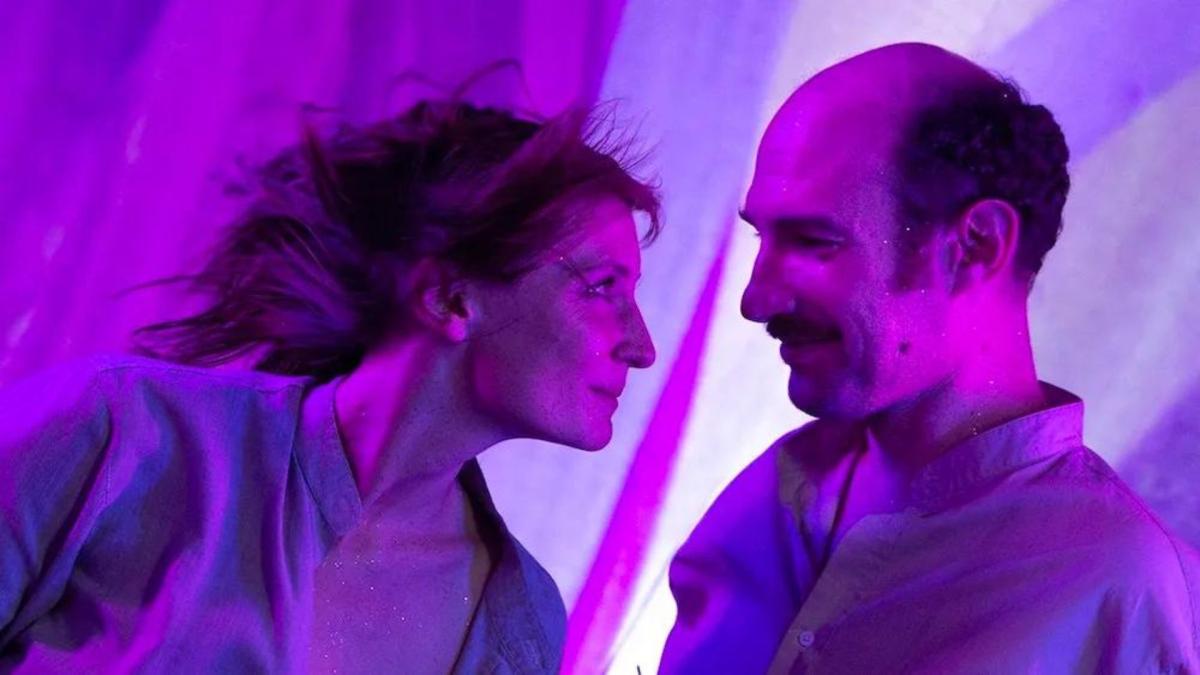 man and woman looking closely at each other in room with purple lights