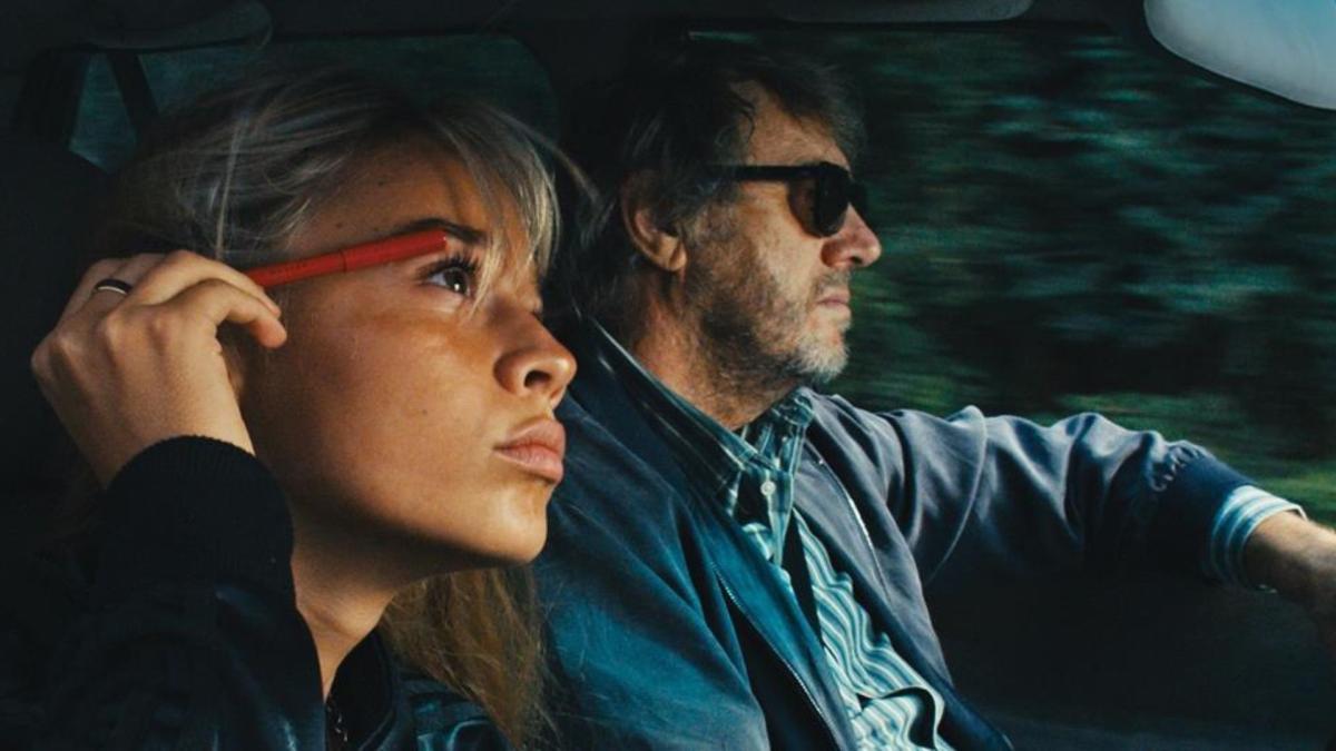 couple driving in car while woman does eye makeup in mirror