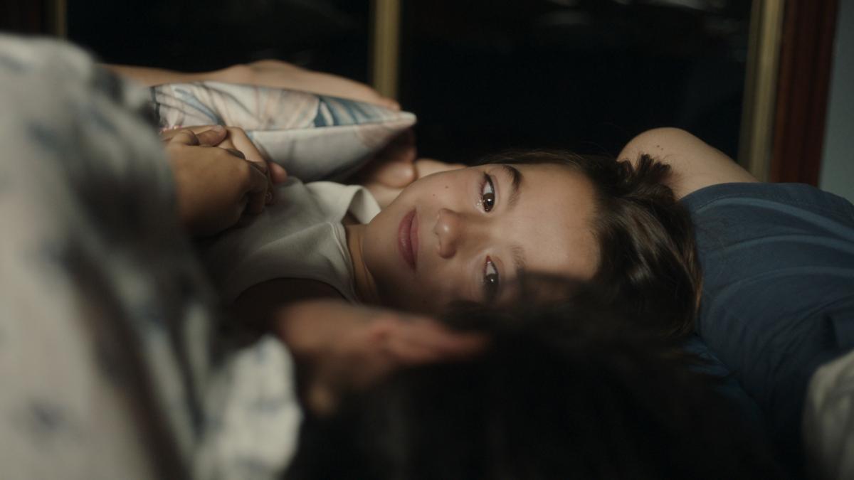 young girl laying on bed looking towards her side