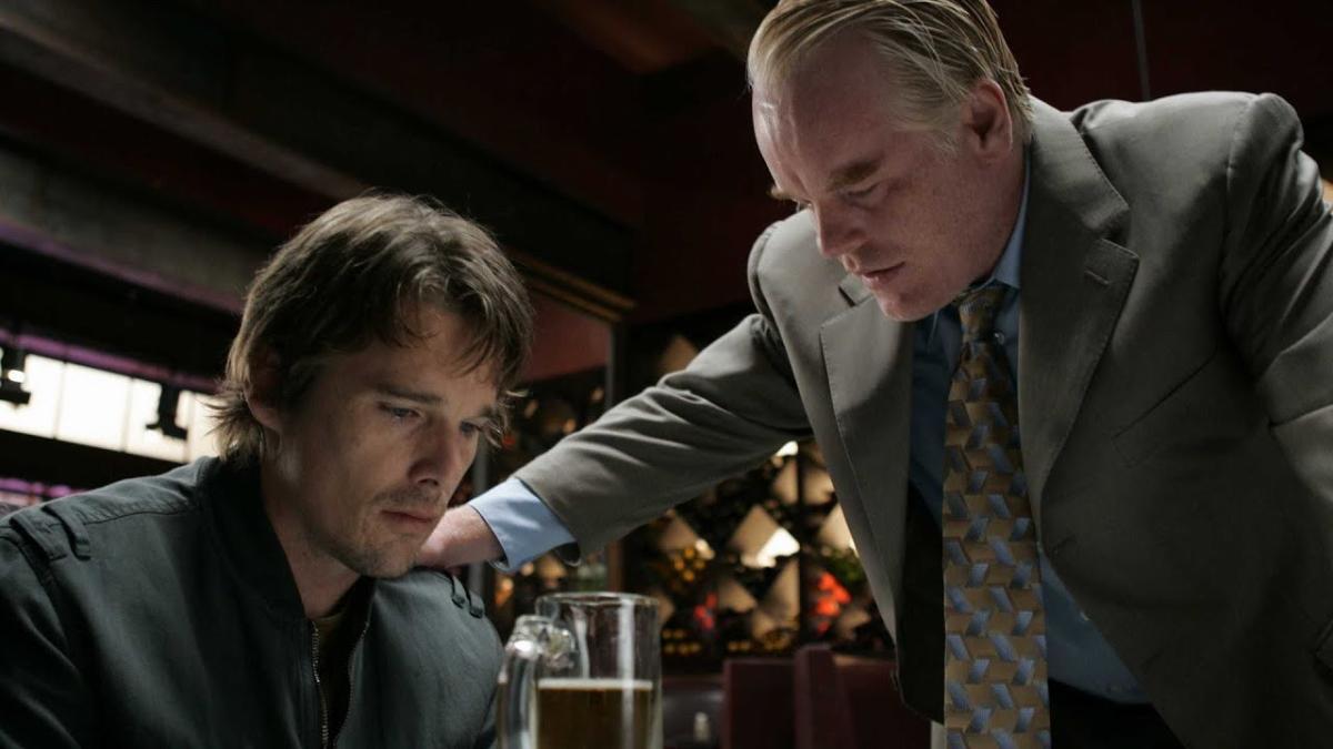 man in suit leaning over seated man in suit with arm on shoulder