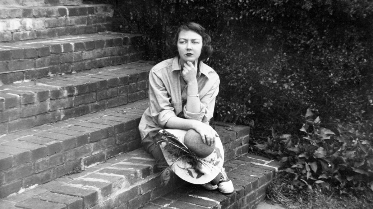 black and white photo of woman in dress sitting on steps with chin resting on fist